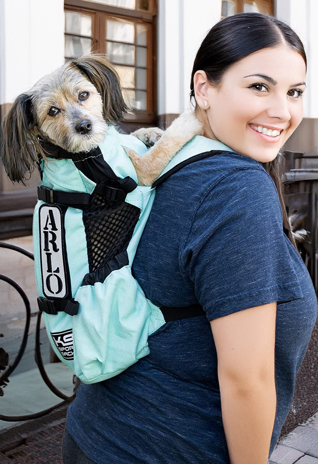 Small dog in an adjustable dog carrier backpack worn by woman outdoors – pet travel carrier for small to medium dogs